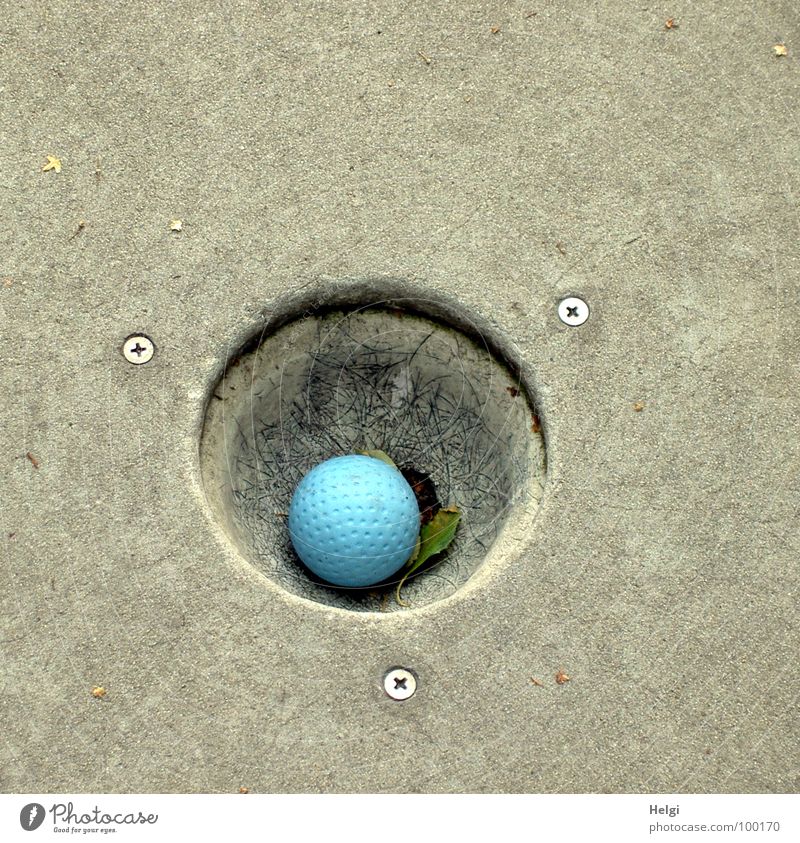 Minigolfball eingelocht auf einer Minigolfanlage Golfball Spielen Sommer grau Freizeit & Hobby rund Sportveranstaltung Erfolg verlieren Verlierer Zeitvertreib