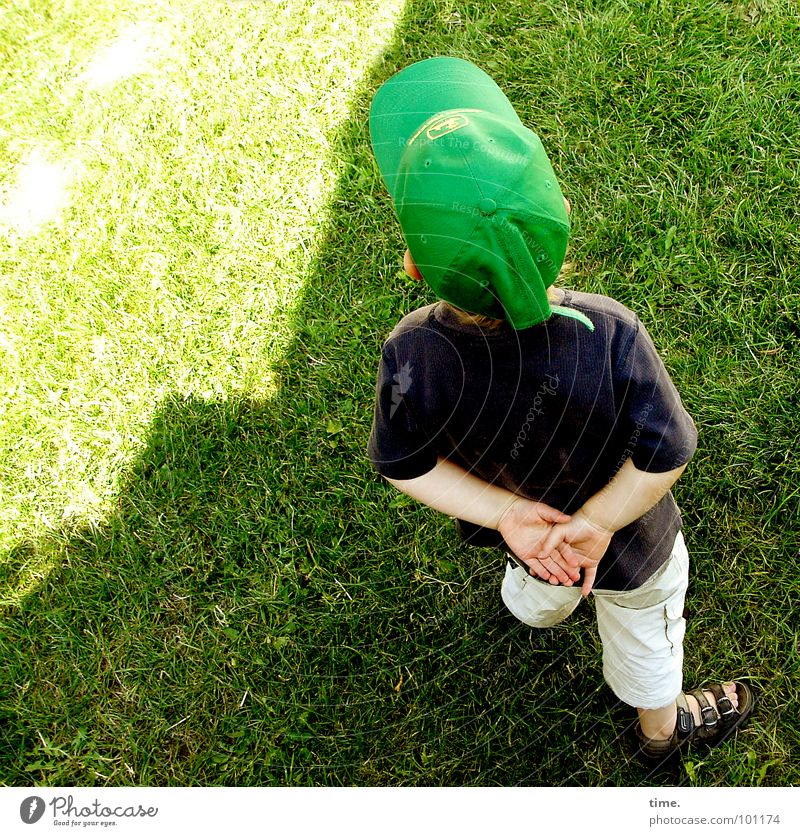 Kleiner Philosoph Licht Schatten Blick Zufriedenheit Sommer Sonne Junge Rücken Wiese Denken grün Konzentration Baseballmütze Sandale Kappe Rasen gefaltete Hände