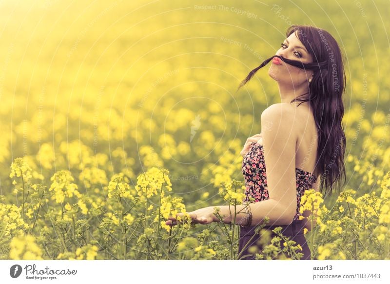 Lustig schönes Frühlingsmädchen mit Haarschnurrbart in gelber Wiese. Attraktives glückliches junges Mädchen, das die warme Sommersonne und seine Gesundheit in einer weiten grünen und gelben Wiese genießt. Teil einer Serie.