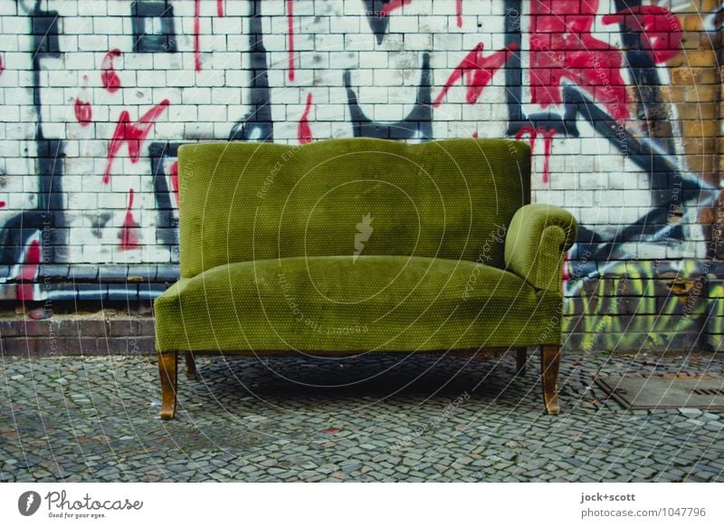 Unvollständiges Sofa steht  auf dem Bürgersteig Subkultur Straßenkunst Kreuzberg Mauer Backstein Graffiti Pfeil kaputt retro grün Unbekümmertheit Sperrmüll