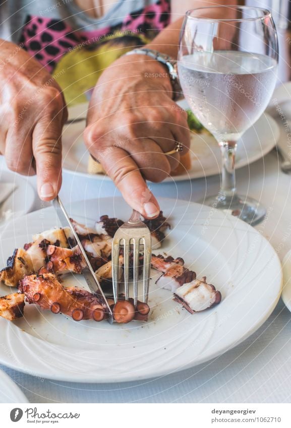Oktopus in einem griechischen Restaurant. Die Hände schneiden den Tintenfisch. Meeresfrüchte Käse Gemüse Mittagessen Abendessen Diät Teller Tisch Kultur Tier