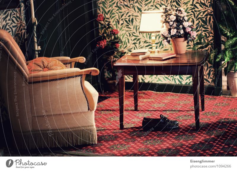 HMV-im Wohnzimmer Sessel Schuhe Tisch Lampe Blumentopf Buch Tapetenmuster alt Teppich Großmutter Farbfoto Innenaufnahme Menschenleer Textfreiraum rechts