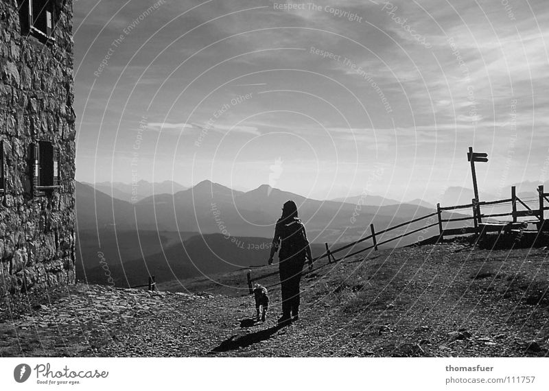 einfach losgehen - Frau mit Hund wandern im Hochgebirge sw Abendsonne Schlagschatten Wolken Begleiter Ferne Hoffnung Selbstvertrauen schön Schwarzweißfoto