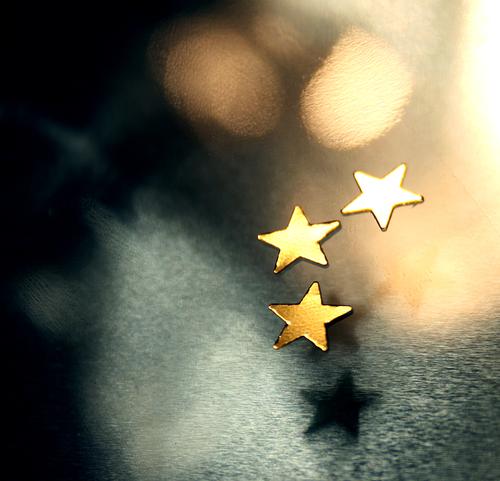 Drei goldene Sterne auf unscharfem Hintergrund mit Lichtern und schönem Bokeh; Weihnachten, Advent Weihnachtsdekoration Spielen Winter Dekoration & Verzierung