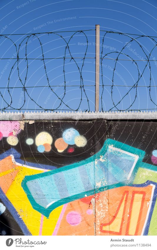 Hübsche Mauer mit Stacheldraht Graffiti Wolkenloser Himmel Sommer Wand Beton Betonmauer Berliner Mauer Stein Metall authentisch bedrohlich Fröhlichkeit gruselig