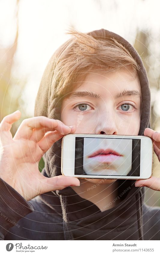 Jungendlicher hält sich ein Handy vor den Mund mit einem Foto von seinem Mund auf dem Display Lifestyle Stil Design Telekommunikation PDA Technik & Technologie