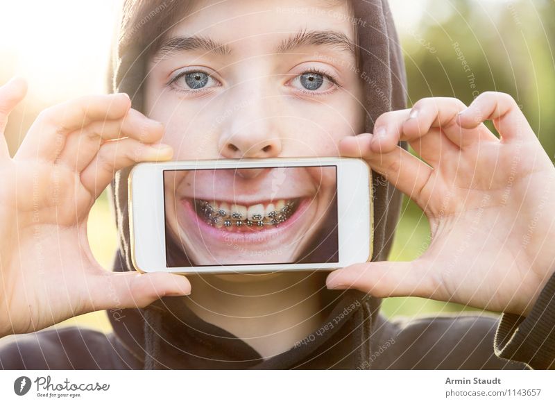 Jugendlicher hält sich Handy vor den Mund mit einem Bild seines Mundes Lifestyle Stil Design Freude Zähne zeigen Telekommunikation PDA Technik & Technologie