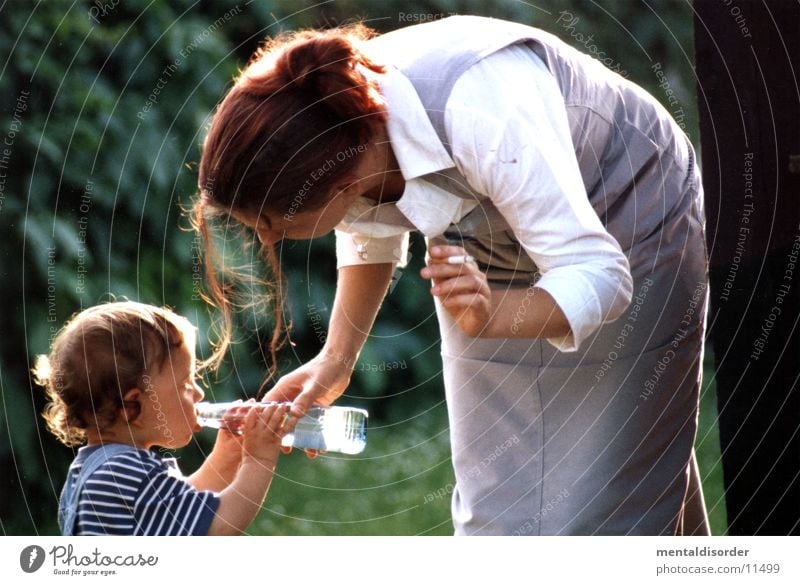 helfende Hand Mutter Frau Sohn Liebe Junge Flasche Wasser im Grünen