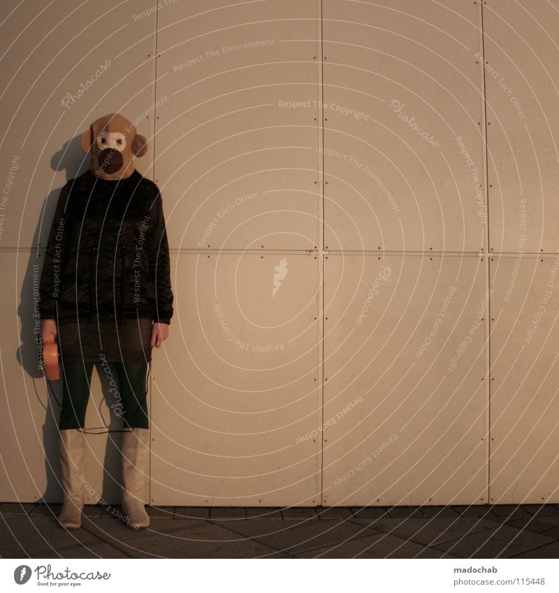 Frau steht mit Maske an einer urbanen Wand und hält einen Fön in der Hand jung Hipster Fashion Zirkus Lifestyle Nachtleben Entertainment Party Veranstaltung