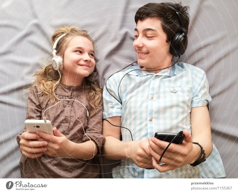 Topaufnahme von Bruder und Schwester beim gemeinsamen Musikhören über Smartphones Freude Glück Mädchen Junge Geschwister Familie & Verwandtschaft 2 Mensch