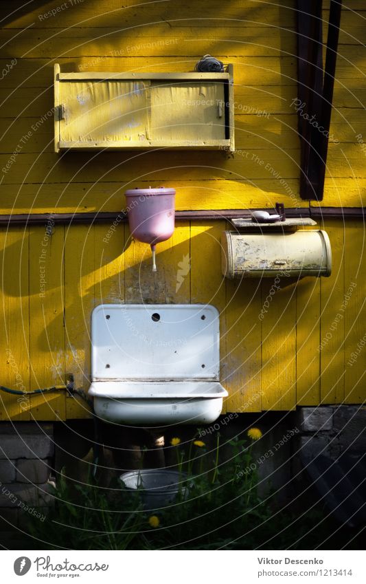 Rosafarbenes Waschbecken auf der gelben Wand des alten Landhauses Stil Design Haus Möbel Bad Metall dreckig grün schwarz weiß Wasserhahn Hintergrund heimwärts