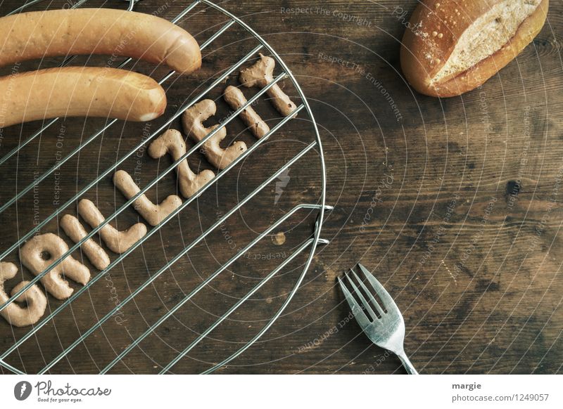 Die Buchstaben GRILLZEIT auf einem Grill, zwei Würstchen, einem Brötchen und einer Gabel auf einem rustikalen Holztisch Lebensmittel Fleisch Wurstwaren Grillen