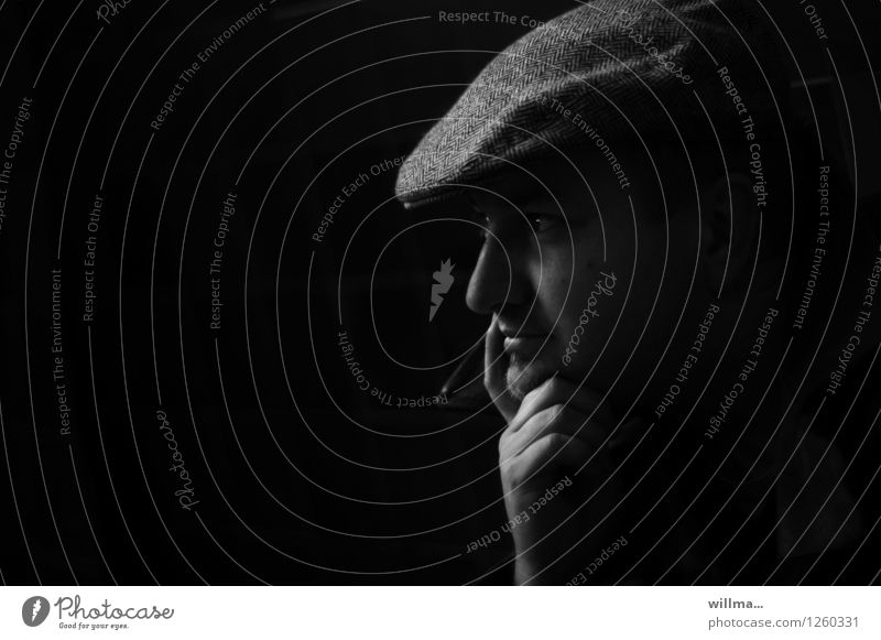 Nachdenklicher junger Mann mit Schiebermütze vor schwarzem Hintergrund Kopf Hand Schirmmütze dunkel nachdenklich aufstützen beobachten Denken Profil Wegsehen