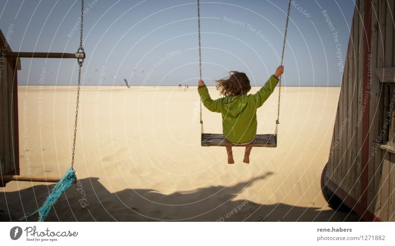 Kind auf einer Schaukel an einem langen Sandstrand kind Blick von Hinten blauer Himmel Nordsee niederlande Entspannung