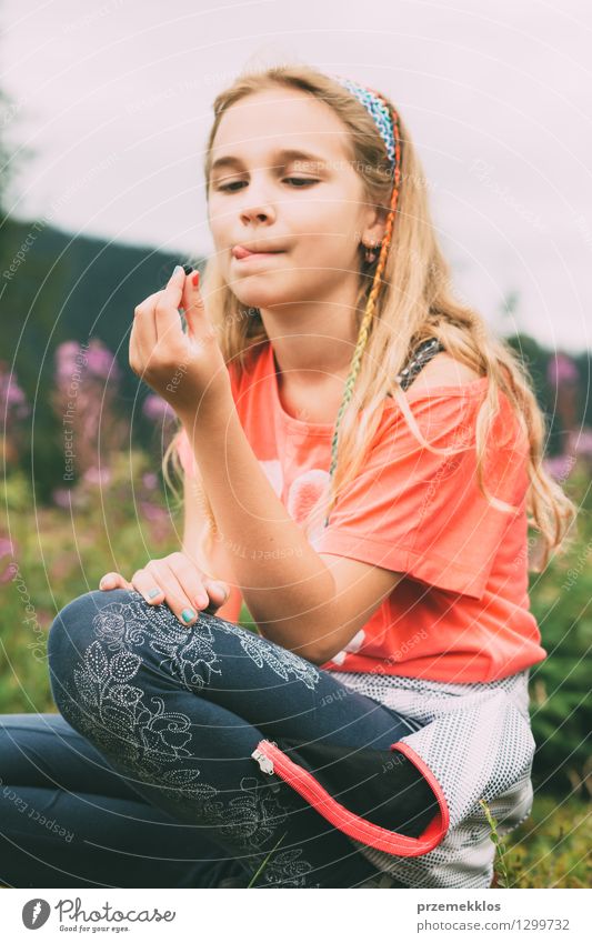 Mädchen, das Blaubeere hält Frucht Kind 1 Mensch 8-13 Jahre Kindheit blond lecker Freude Blaubeeren Verkostung Zunge Farbfoto Außenaufnahme Tag Porträt