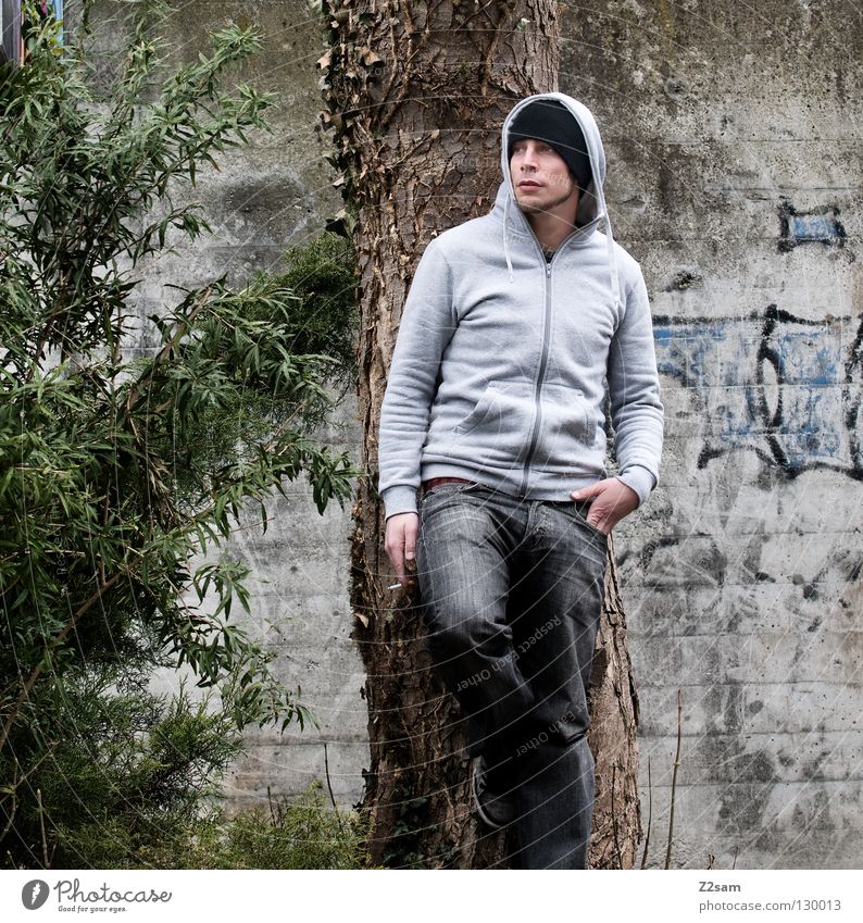 raucherpause Mann Jugendliche stehen Rauchen Mütze Baum grün Sträucher Stil Mensch Körperhaltung Kapuze baum wand Graffiti Jeanshose anlehnen Blick Beine
