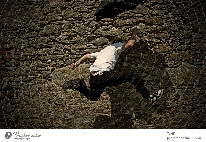 auf auf und davon springen Regenschirm Mann T-Shirt weiß schwarz braun steinig Wand Mauer Steinwand Steinmauer Putz Schlagschatten Fröhlichkeit heiter