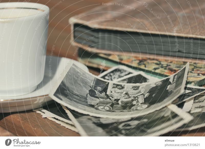 alte Papierbilder, Fotoalben und eine kleine Tasse auf einem Tisch Fotografie Fotoalbum Buch Roman Erzählung Vergangenheit historisch einzigartig Originalität