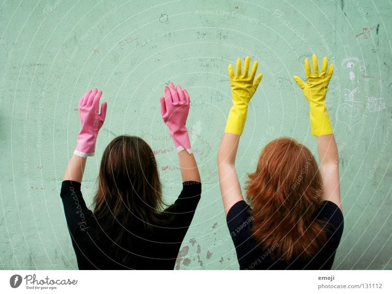 Zwei nicht identifizierbare Frauen mit Handschuhen Gummi rosa gelb knallig Rauschmittel türkis Wand beschrieben dreckig Reinigen edel skurril seltsam Karneval