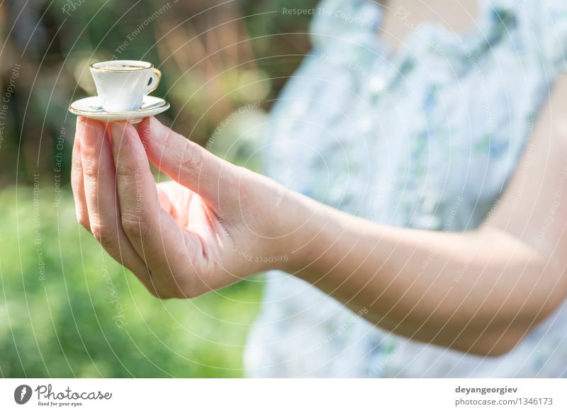 Hand halten sehr kleine Tasse Kaffee. Stil Garten Tisch Frau Erwachsene heiß retro weiß Farbe Miniatur Café Halt Overhead altehrwürdig Untertasse Menschen