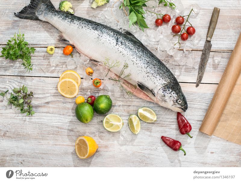 Rohe Lachsfische in Eis und Gemüse Meeresfrüchte Abendessen Tisch Koch Papier frisch lecker rot weiß Fisch Lebensmittel roh Zitrone Backpapier Messer hölzern