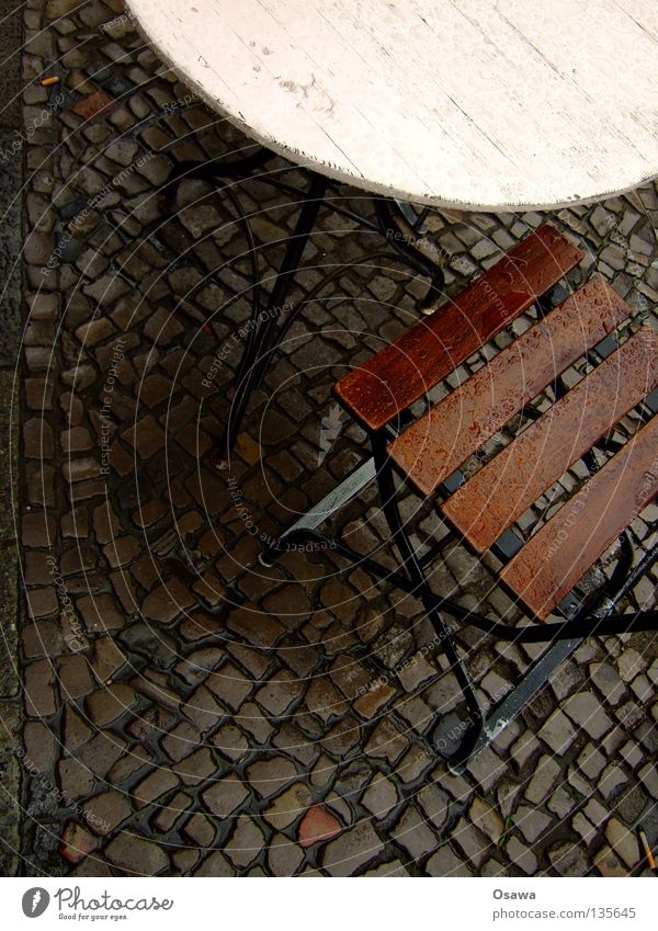 Schwarzes Cafe Café Straßencafé Tisch Möbel Regen nass Regenwasser Bürgersteig Kopfsteinpflaster ungemütlich Stuhl Sitzgruppe Wasser ins Wasser gefallen
