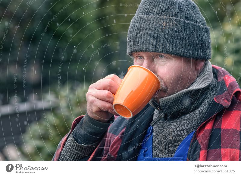 Mann in trinkendem Kaffee der gestrickten Wollmütze Getränk Gesicht Winter Schnee Handwerker Erwachsene Wetter Wärme Jacke Schal Hut heiß Konzentration Beanie