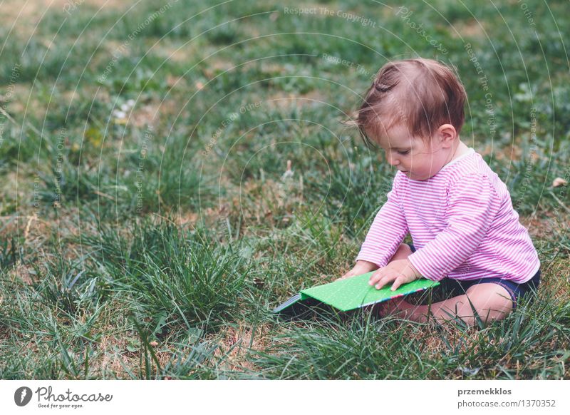 Kleines Baby, das ein Buch mit Bildern überwacht Lifestyle Freude Glück schön Leben Spielen Kind Mensch Kleinkind Mädchen Kindheit 1 0-12 Monate Gras Garten