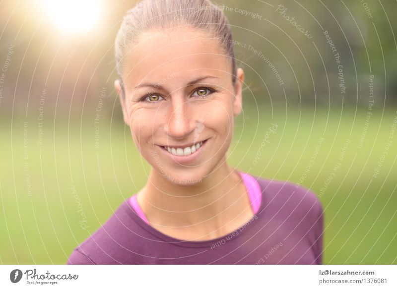 Geeignete Frau, die die Kamera lächelt und betrachtet Gesicht Sport Erwachsene Zähne Park Lächeln vor der Kamera passen Lichtschein zahnfarben jung Farbfoto