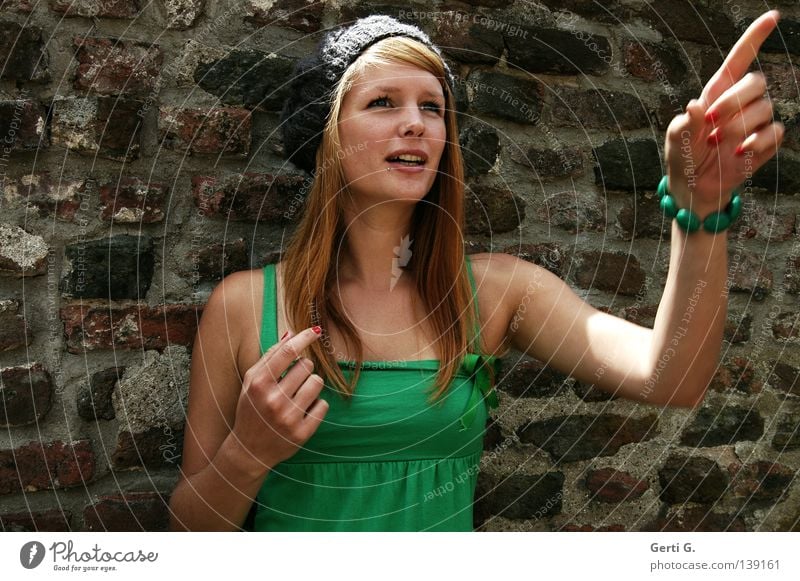 *staun erstaunt Überraschung Hinweis Zeigefinger Hand Armband Frau Junge Frau schön grün langhaarig rothaarig Mütze T-Shirt Gesichtsausdruck Richtung Mauer Wand