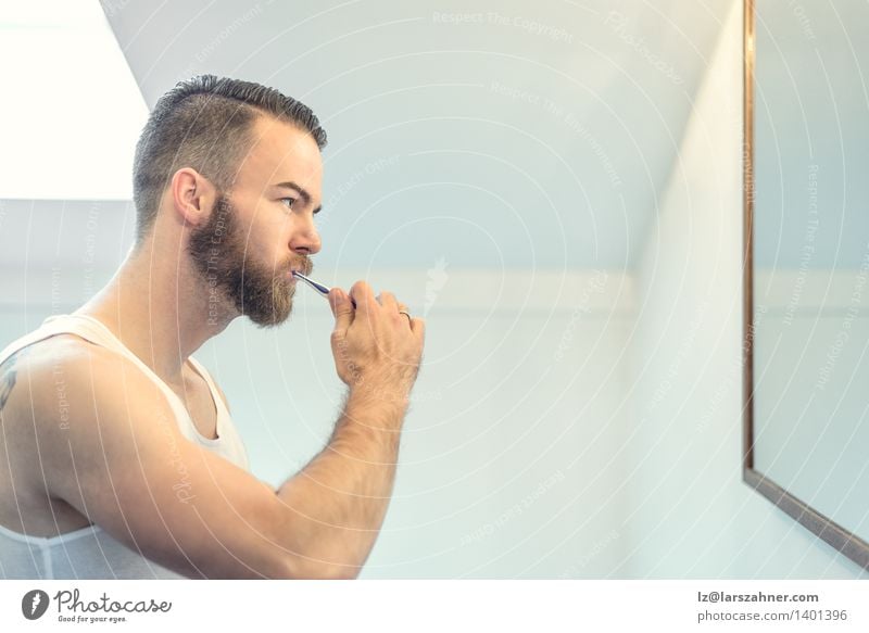 Junger bärtiger Mann, der seine Zähne putzt Gesicht Gesundheitswesen Spiegel Bad Erwachsene Vollbart Zahnbürste modern Sauberkeit bürstend Pflege Karies