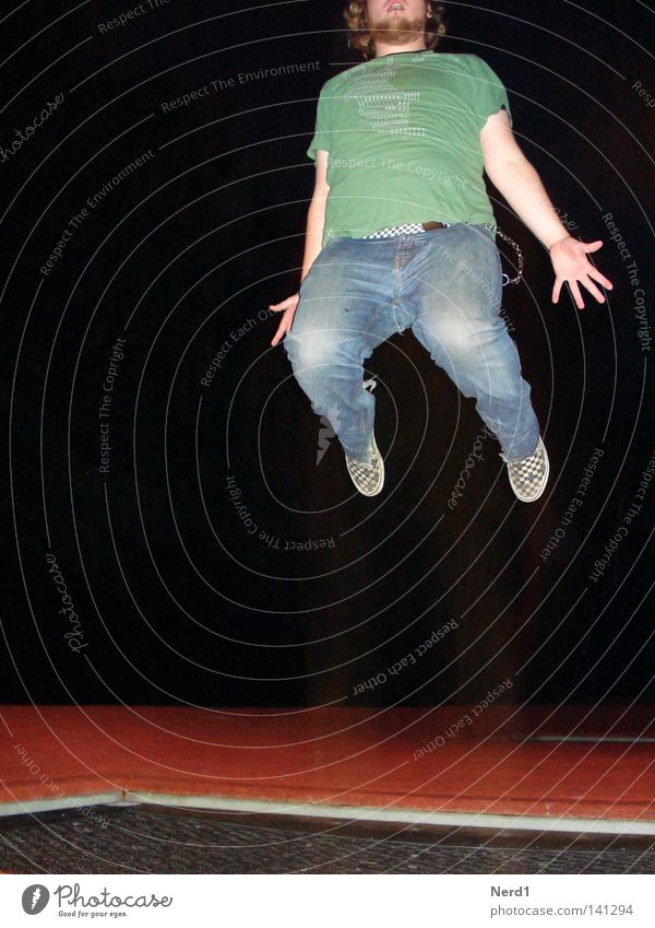 Jump rot springen Trampolin Jeansstoff Mann Bart Hand grün Nacht schwarz Freude anstrengen Hose Beine Finger T-Shirt dunkel hüpfen Bewegungsenergie Schwerkraft