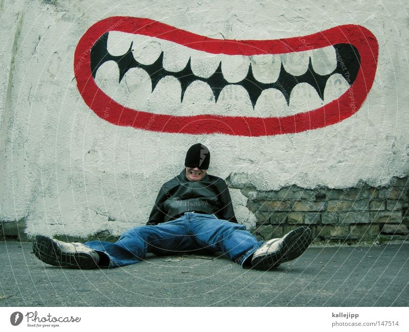 grins nicht so blöd! grinsen lachen Humor Witz Gelächter Graffiti Aufschrift Mund Zähne Zahnarzt dental Spaßvogel Joker Mann Mensch sitzen anlehnen Wand