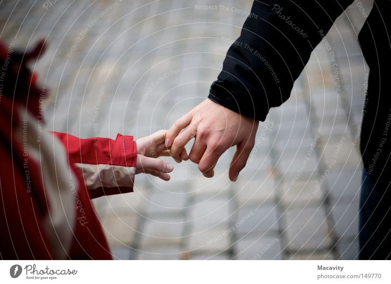 Nicht loslassen Vertrauen Freundschaft Kind Mann Frau Partnerschaft Hand Finger greifen Kopfsteinpflaster Anorak berühren Verbindung rot grau klein Jacke kalt