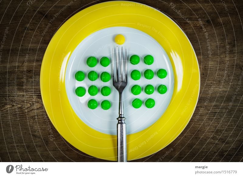 Auf den Punkt! Aufgespießt! Ein Teller mit gelben Rand und grüne Erbsen gut geordnet, eine Gabel und eine gelbe Pille Lebensmittel Dessert Ernährung Frühstück