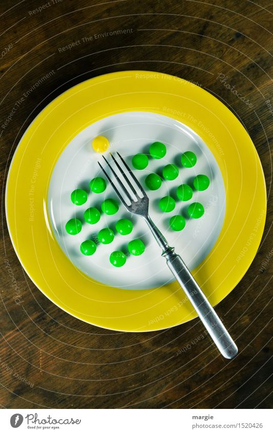 Aufgespießt! Ein Teller mit gelben Rand und grüne Erbsen gut geordnet, eine Gabel und eine gelbe Pille Lebensmittel Dessert Ernährung Frühstück Mittagessen