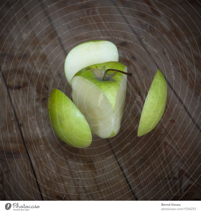 Schnittgut Lebensmittel Frucht Apfel Ernährung Vegetarische Ernährung lustig grün Schweben Holzfußboden Trick Dreieck Abtrennung Teilung explosionszeichnung