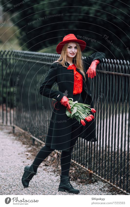 Frau, die auf dem Parkhintergrund mit Blumen steht elegant Stil schön Garten Mensch Mädchen Erwachsene Natur Wetter Tulpe Mode Bekleidung Pullover Pelzmantel