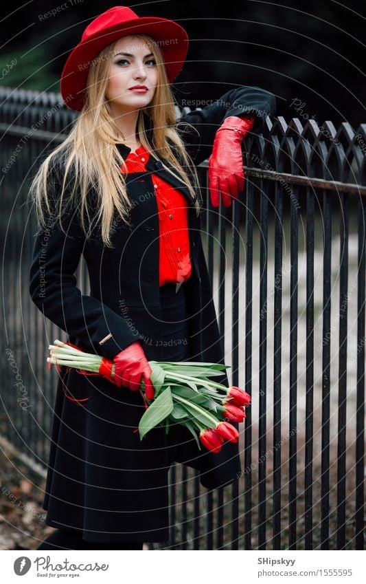 Frau, die auf dem Parkhintergrund mit Blumen steht elegant Stil schön Garten Mensch Mädchen Erwachsene Natur Wetter Tulpe Mode Bekleidung Pullover Pelzmantel