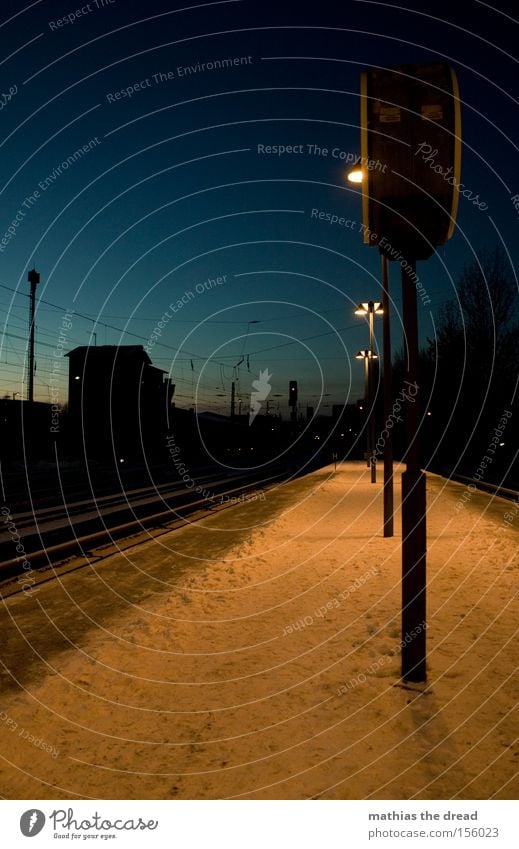 NÄCHTLICHES WARTEN Bahnsteig Gleise Hochspannungsleitung Kabel Laterne Kunstlicht Schnee Dämmerung blau Haus Silhouette Menschenleer Einsamkeit ruhig Stadt