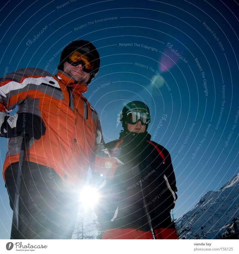Skihasen Skifahrer Skifahren Skier Sport Wintersport Mann Sportler kalt Helm Brille Freundschaft 2 Schnee Gipfel Blende Blendenfleck stehen Himmel blau