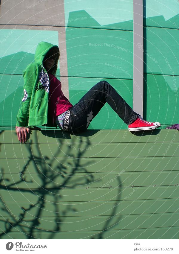 Lärmschutzwand Frau Erwachsene Mauer Wand sitzen grün Einsamkeit Chucks lärmschutzwand Farbfoto mehrfarbig Außenaufnahme Tag Sonnenlicht Ganzkörperaufnahme