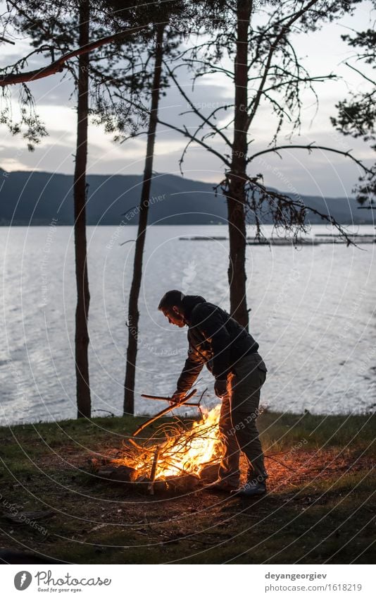 Mann beleuchtet ein Feuer im Kamin in der Natur nachts Freizeit & Hobby Ferien & Urlaub & Reisen Tourismus Abenteuer Camping Sommer Berge u. Gebirge wandern