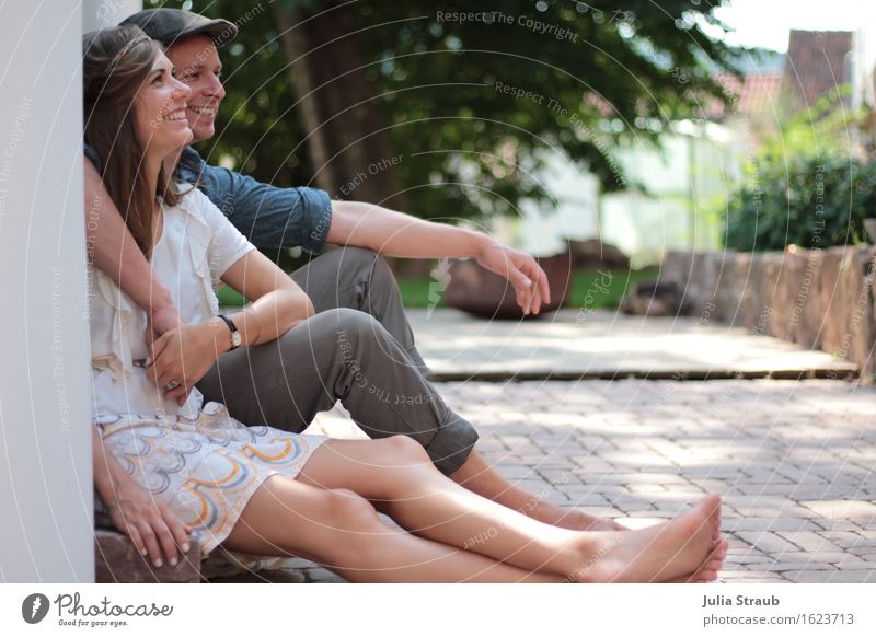 Paar sitzt auf einer kleinen Treppe im Innenhof Sommer Partner Erwachsene 2 Mensch 30-45 Jahre Baum Sträucher Garten Mauer Wand Terrasse Kleid Hut Mütze brünett