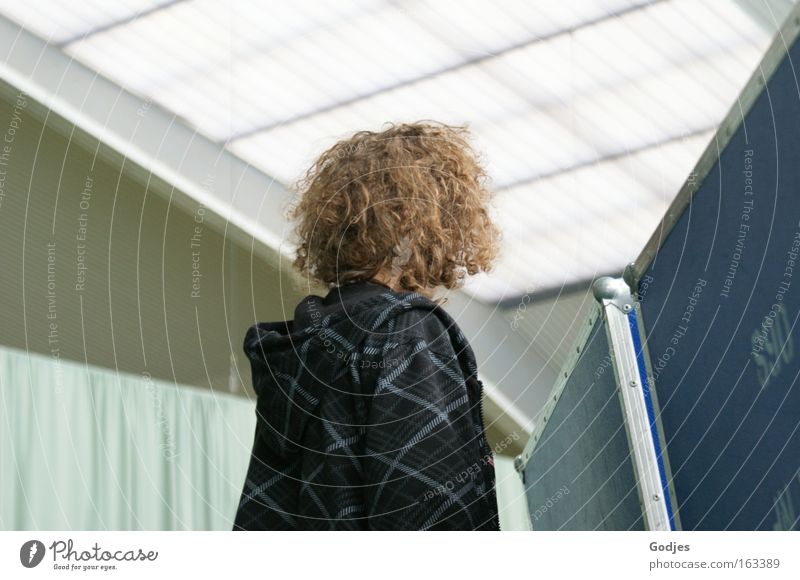 Person mit lockigen Haaren schaut über eine Wand, Gesicht abgewendet Freizeit & Hobby Veranstaltung Sportstätten Bildung Schüler Mensch maskulin Jugendliche