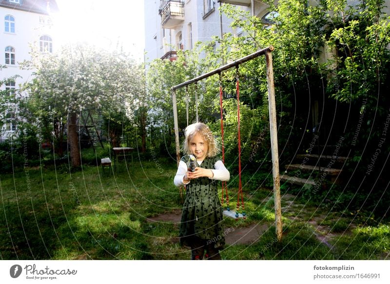 Mädchen mit Wasserpistole im Garten Kinderspiel Schaukel Spielen Lebensfreude leuchten Gefühle Stimmung Freude Idylle Kindheit schießen Lichtstrahl Farbfoto