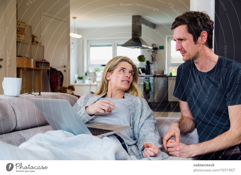 Paar zu Hause auf dem Sofa mit Blick auf den Laptop ruhig Wohnzimmer Computer Notebook Internet Frau Erwachsene Mann sprechen lügen heimwärts Decke Liege