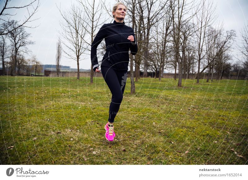 blonde Frau, die im Park läuft. Lifestyle Körper Wellness Winter Sport Joggen Mensch Erwachsene Gras Bewegung Fitness sportlich Geschwindigkeit üben Gesundheit