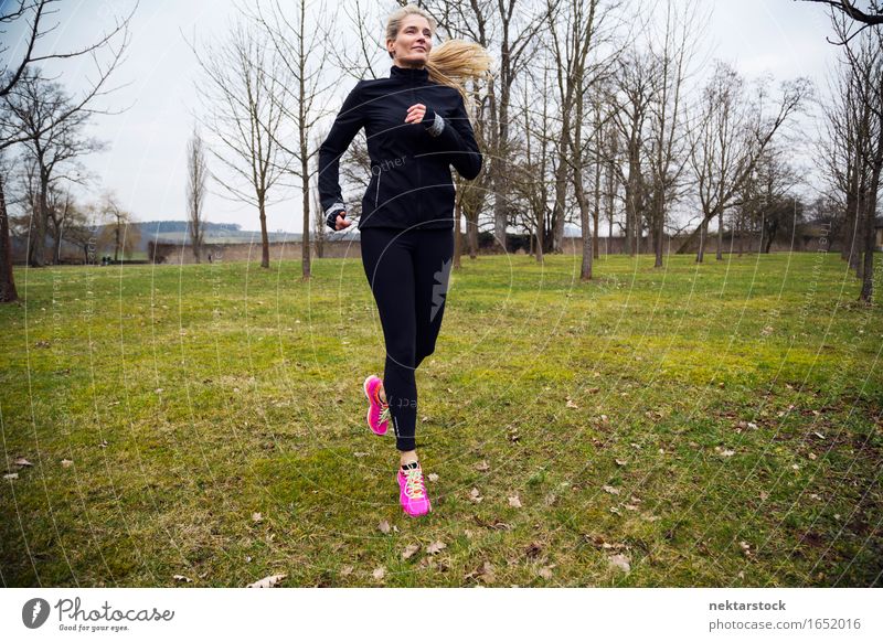 blonde Frau, die im Park läuft. Lifestyle Körper Wellness Winter Sport Joggen Mensch Erwachsene Gras Bewegung Fitness sportlich Geschwindigkeit üben Gesundheit