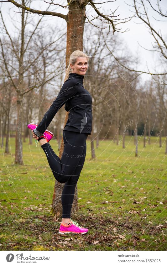 Frau, die ihre Beine im Park ausstreckt. Lifestyle Körper Wellness Sport Mensch Erwachsene Fitness Lächeln stehen sportlich dünn Freundlichkeit